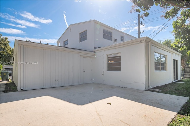 back of property with a patio, driveway, and stucco siding