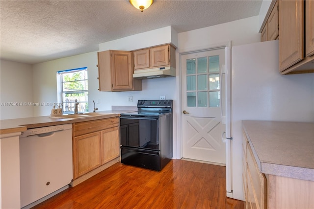 kitchen featuring white appliances, light wood-style floors, light countertops, under cabinet range hood, and a sink