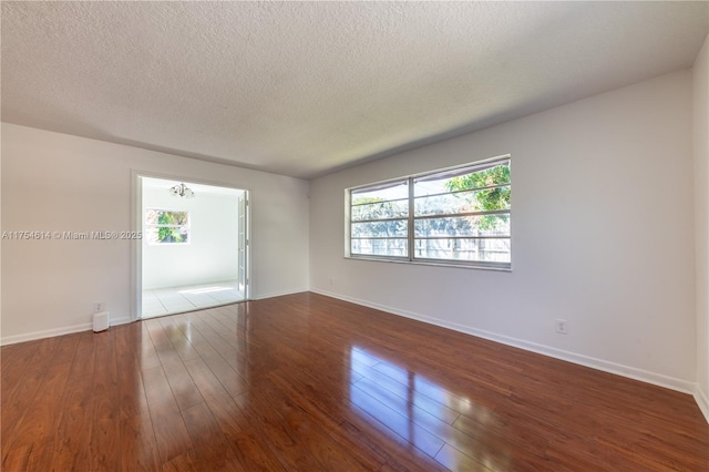 unfurnished room featuring baseboards, a textured ceiling, and hardwood / wood-style floors