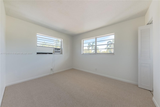 empty room featuring light carpet, a textured ceiling, and baseboards