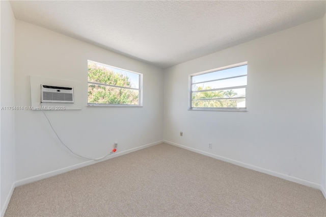 carpeted empty room featuring baseboards, a wall mounted AC, and a textured ceiling