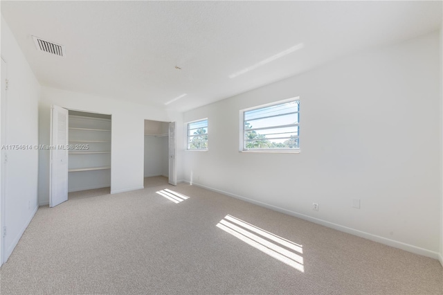 unfurnished bedroom featuring carpet floors, baseboards, multiple closets, and visible vents