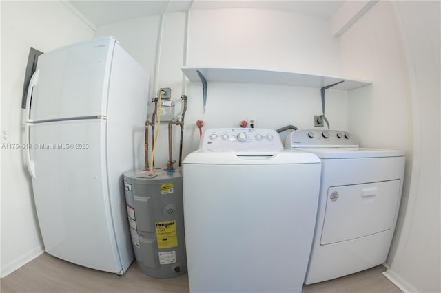 washroom with water heater, independent washer and dryer, laundry area, and light wood-style floors
