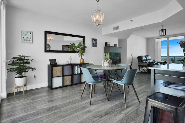 dining area featuring a chandelier, visible vents, baseboards, and wood finished floors