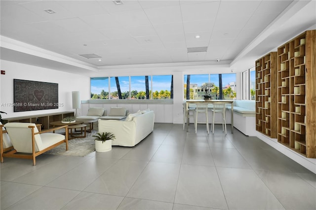 living room featuring a tray ceiling, tile patterned flooring, and a wealth of natural light