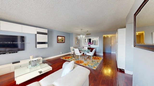 living room featuring dark wood finished floors, a textured ceiling, baseboards, and a chandelier