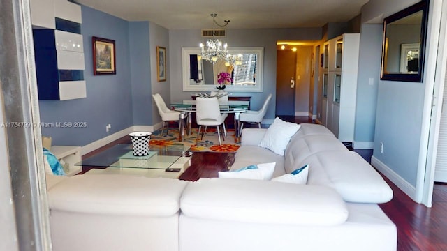 living room with an inviting chandelier, wood finished floors, visible vents, and baseboards