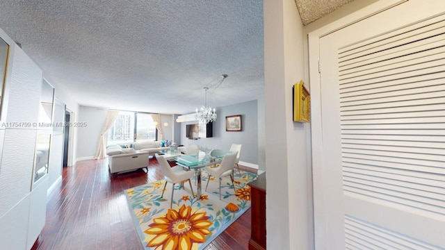 dining area with baseboards, a textured ceiling, an inviting chandelier, and wood-type flooring