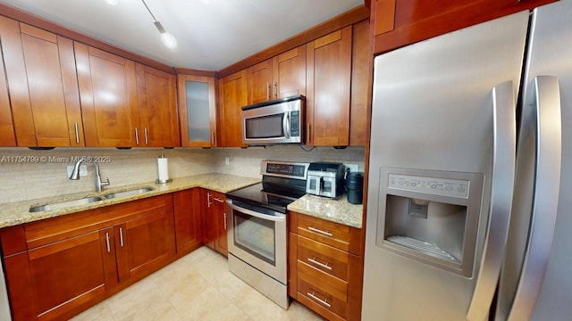 kitchen featuring light stone countertops, stainless steel appliances, glass insert cabinets, and a sink