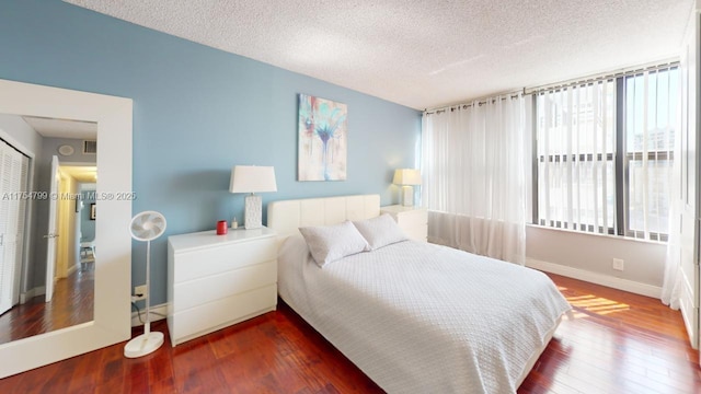 bedroom with a textured ceiling, baseboards, and hardwood / wood-style floors