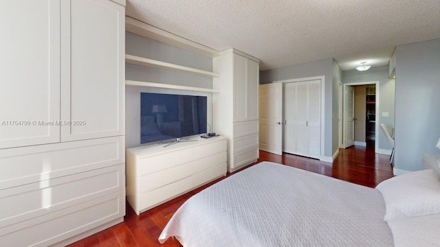 bedroom with a closet, baseboards, a textured ceiling, and dark wood-style floors