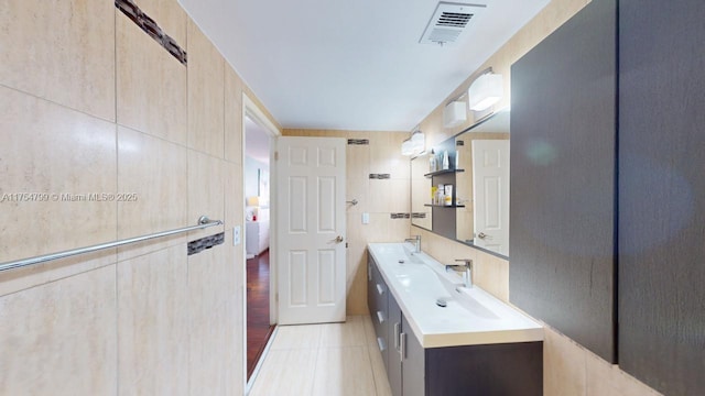 bathroom featuring tile patterned flooring, visible vents, tile walls, and vanity