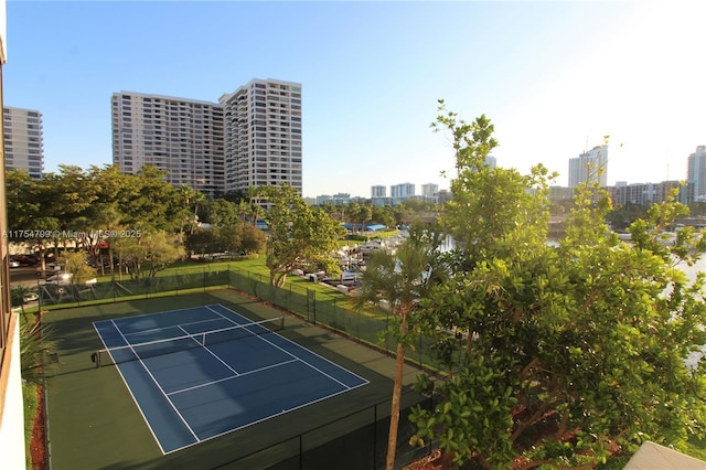 view of tennis court with a city view and fence