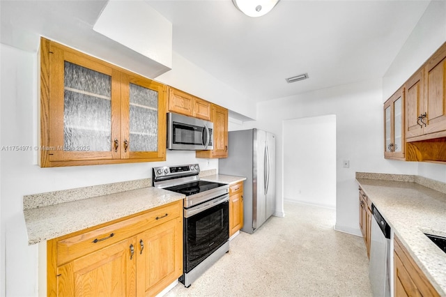 kitchen featuring stainless steel appliances, visible vents, glass insert cabinets, and baseboards