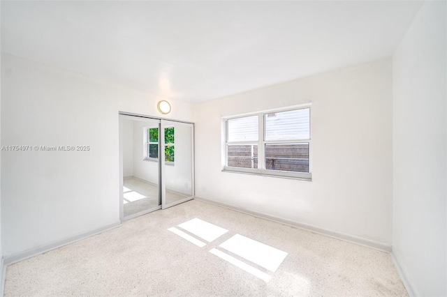 unfurnished bedroom featuring baseboards, a closet, and speckled floor