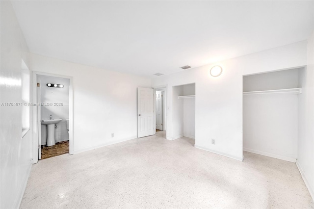 unfurnished bedroom featuring speckled floor, two closets, and visible vents