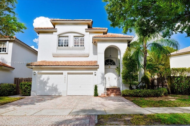 mediterranean / spanish-style house with decorative driveway, fence, and stucco siding