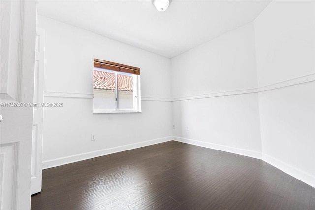 spare room featuring dark wood finished floors and baseboards