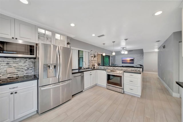 kitchen with a peninsula, appliances with stainless steel finishes, dark countertops, and a sink