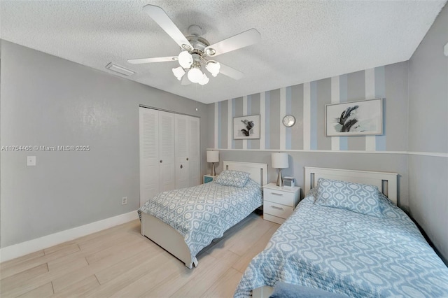 bedroom with a closet, a textured ceiling, baseboards, and wood finished floors