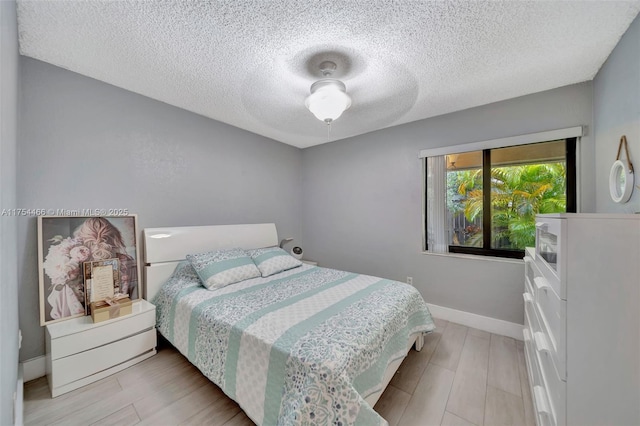 bedroom featuring light wood-style floors, a textured ceiling, and baseboards