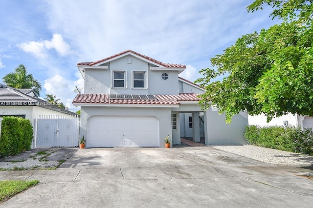 mediterranean / spanish house with fence, a tile roof, driveway, a gate, and stucco siding