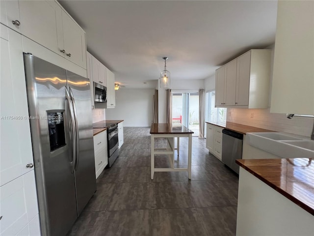 kitchen featuring decorative backsplash, butcher block counters, appliances with stainless steel finishes, white cabinetry, and a sink