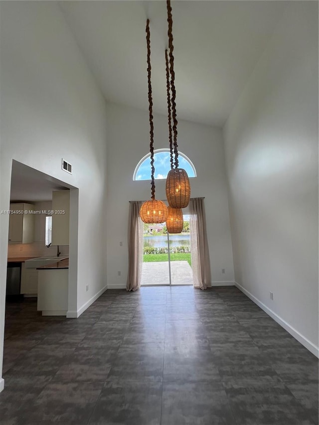 interior space with high vaulted ceiling, visible vents, and baseboards