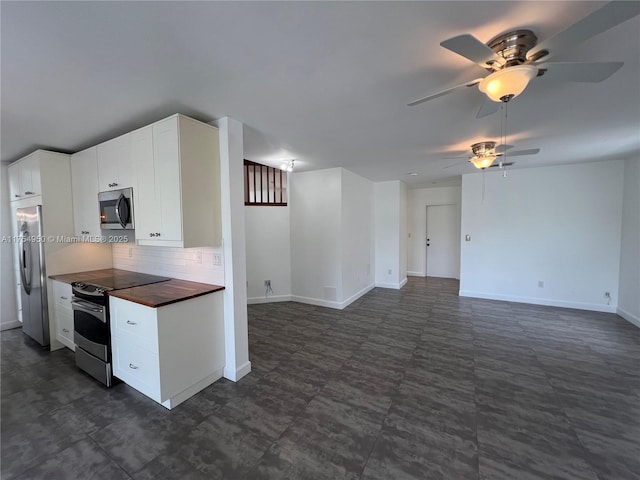 kitchen featuring stainless steel appliances, tasteful backsplash, white cabinetry, butcher block countertops, and baseboards