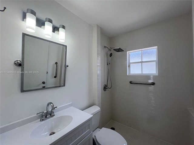 full bath featuring tiled shower, vanity, and toilet