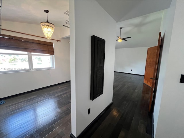 interior space with a chandelier, lofted ceiling, dark wood-style flooring, and baseboards