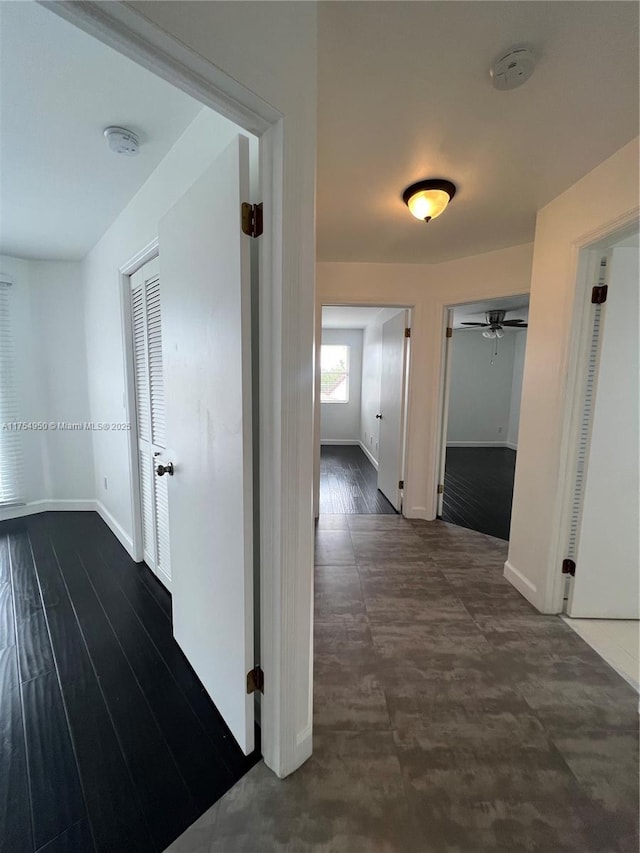 hallway with dark wood finished floors and baseboards