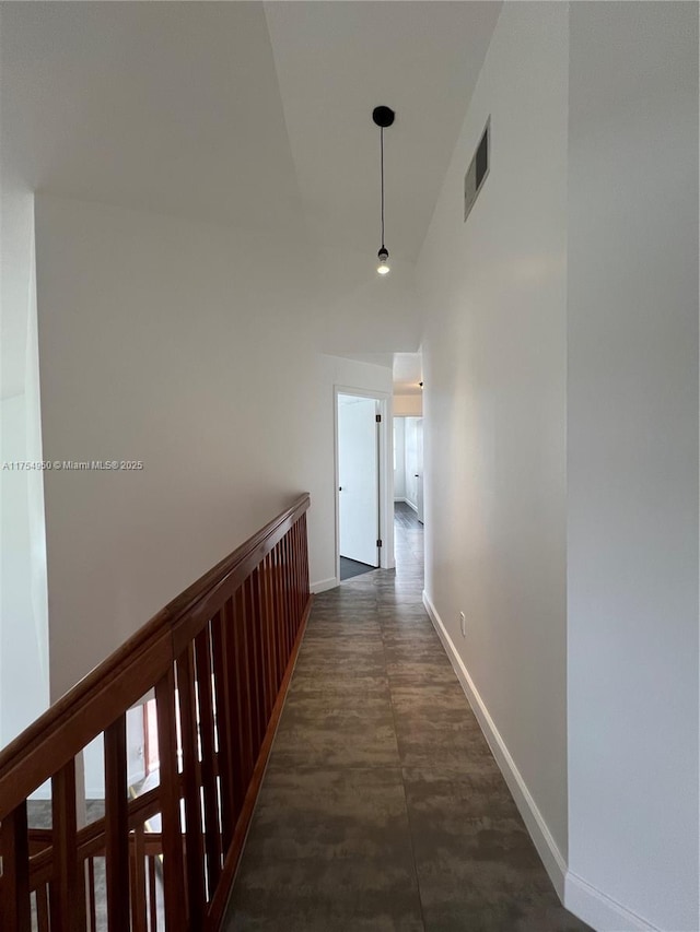 hallway with high vaulted ceiling, visible vents, and baseboards