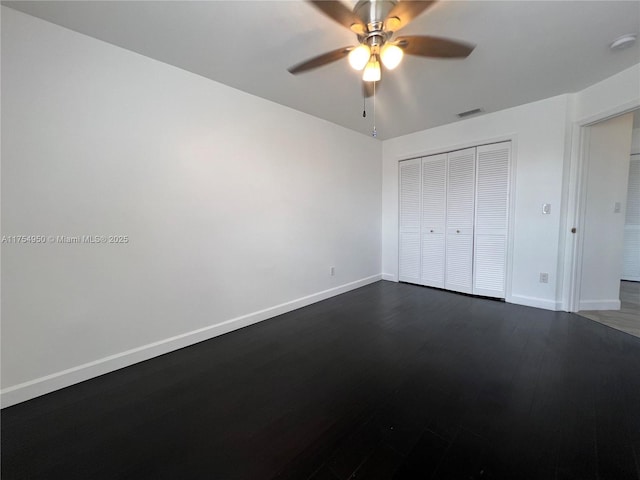 unfurnished bedroom with dark wood-style floors, a closet, visible vents, and baseboards