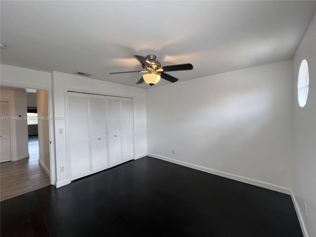 unfurnished bedroom featuring baseboards, a closet, visible vents, and dark wood-type flooring