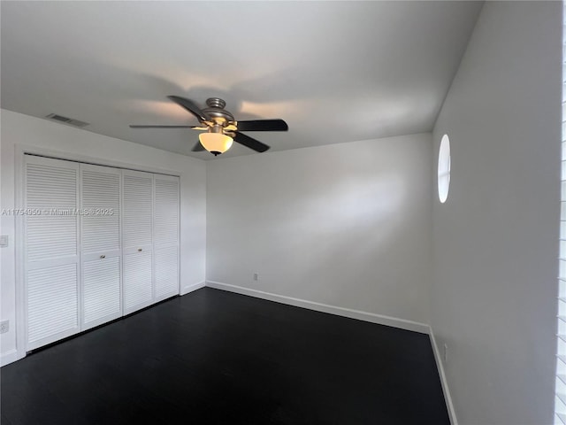 unfurnished bedroom with dark wood-type flooring, a closet, visible vents, and baseboards