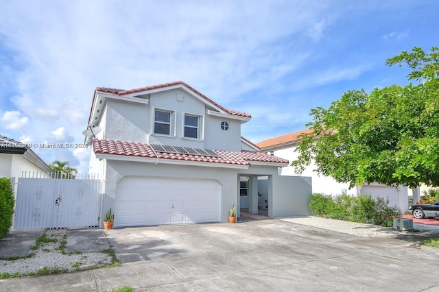 mediterranean / spanish-style home with driveway, a garage, a tiled roof, fence, and stucco siding