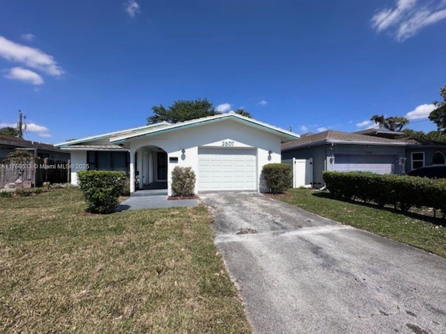 single story home featuring stucco siding, an attached garage, fence, driveway, and a front lawn