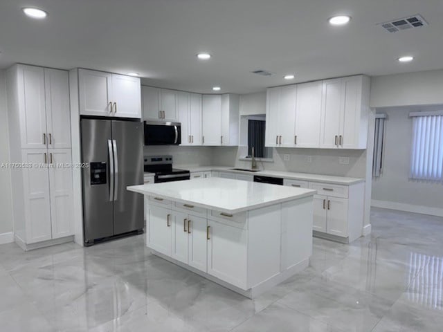 kitchen featuring stainless steel appliances, a sink, visible vents, white cabinets, and backsplash