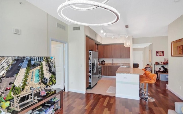 kitchen with brown cabinetry, visible vents, stainless steel refrigerator with ice dispenser, and a sink