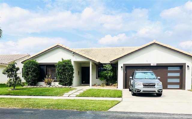 ranch-style house featuring a garage, a tiled roof, a front lawn, and stucco siding