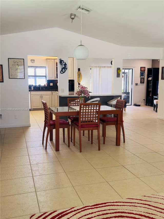 dining space with visible vents, light tile patterned flooring, and vaulted ceiling