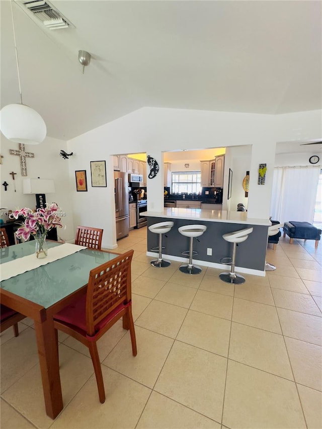 dining area with visible vents, vaulted ceiling, and light tile patterned floors