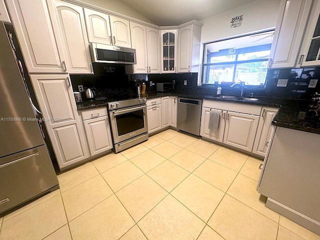 kitchen with light tile patterned flooring, a sink, backsplash, and stainless steel appliances