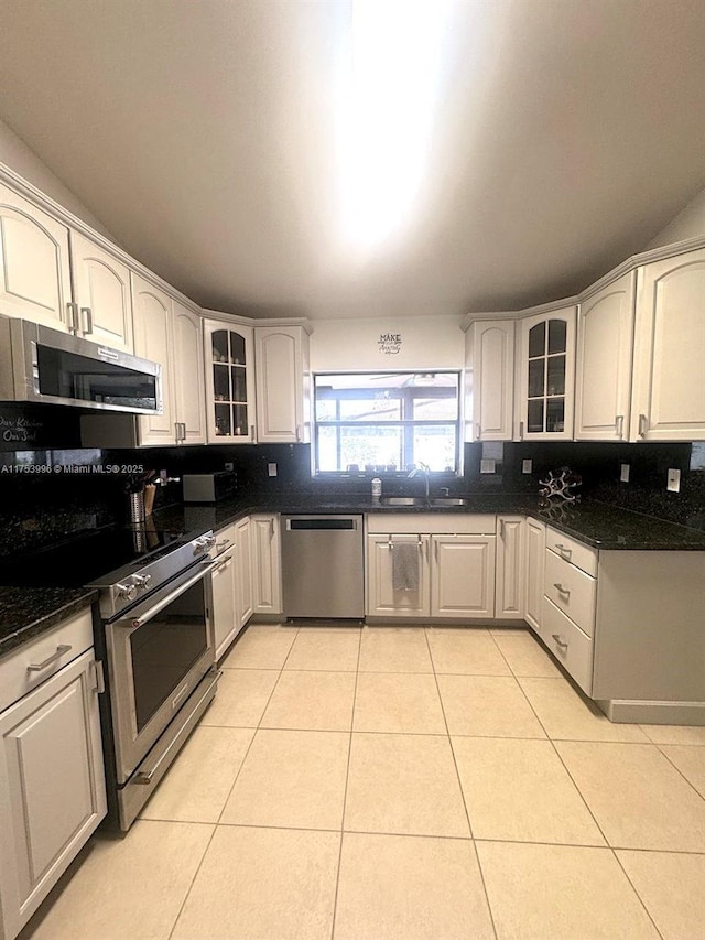 kitchen featuring a sink, backsplash, light tile patterned flooring, and stainless steel appliances