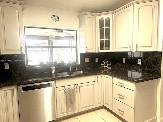 kitchen featuring dishwasher, a sink, backsplash, and glass insert cabinets
