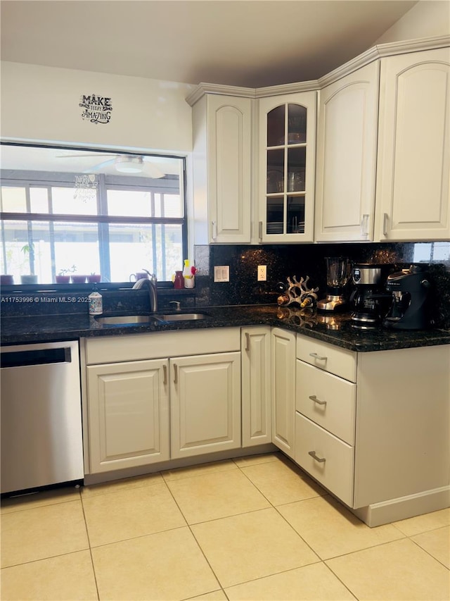kitchen with light tile patterned floors, white cabinets, dishwasher, a sink, and decorative backsplash