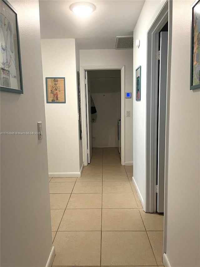 corridor with visible vents, baseboards, and light tile patterned flooring