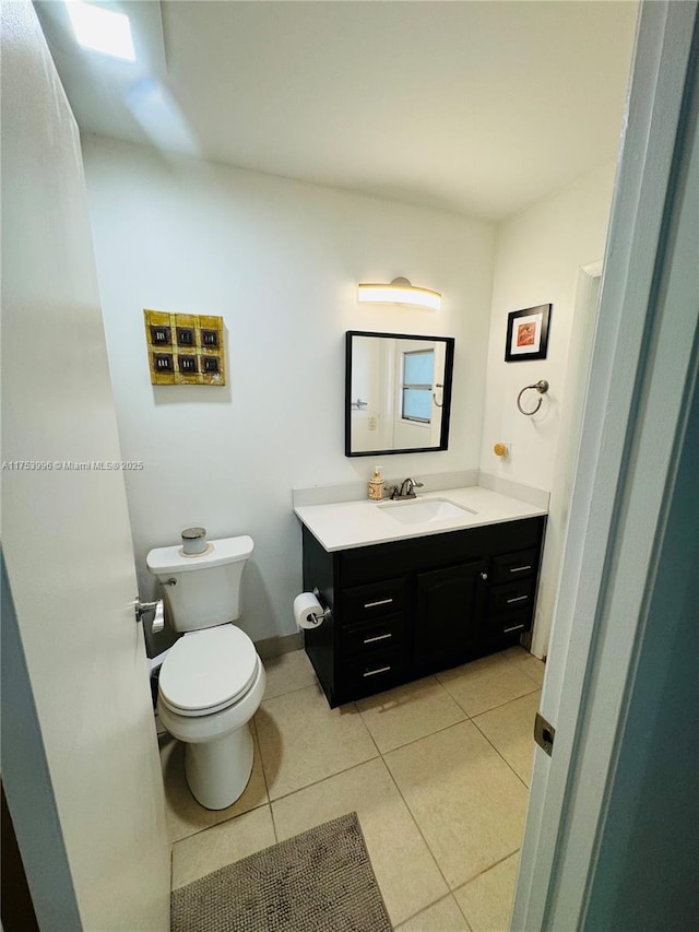 half bath with toilet, tile patterned flooring, and vanity