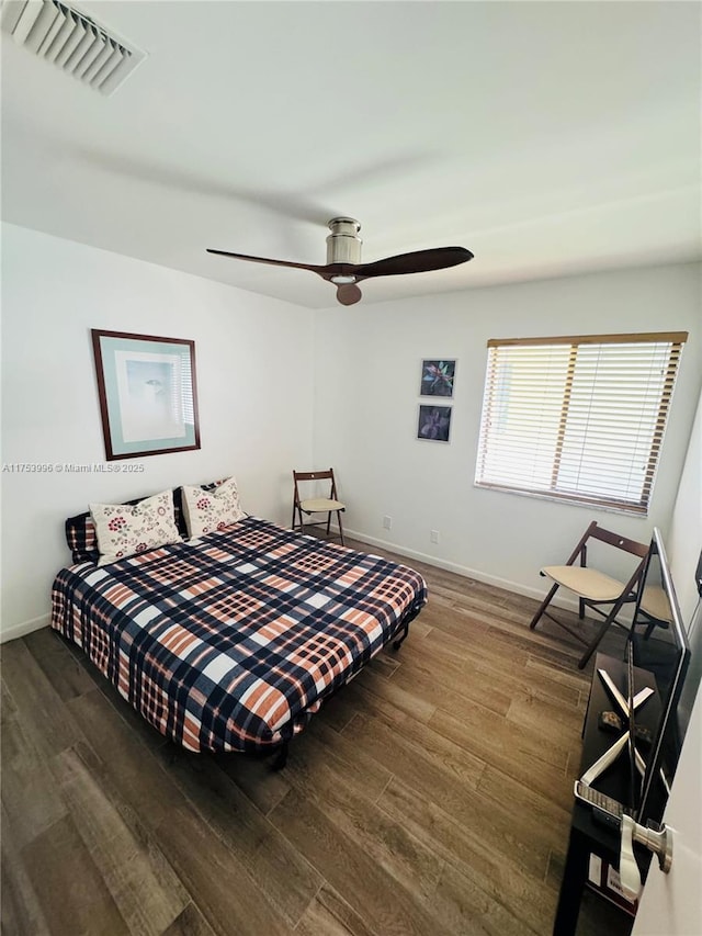 bedroom featuring visible vents, baseboards, a ceiling fan, and wood finished floors